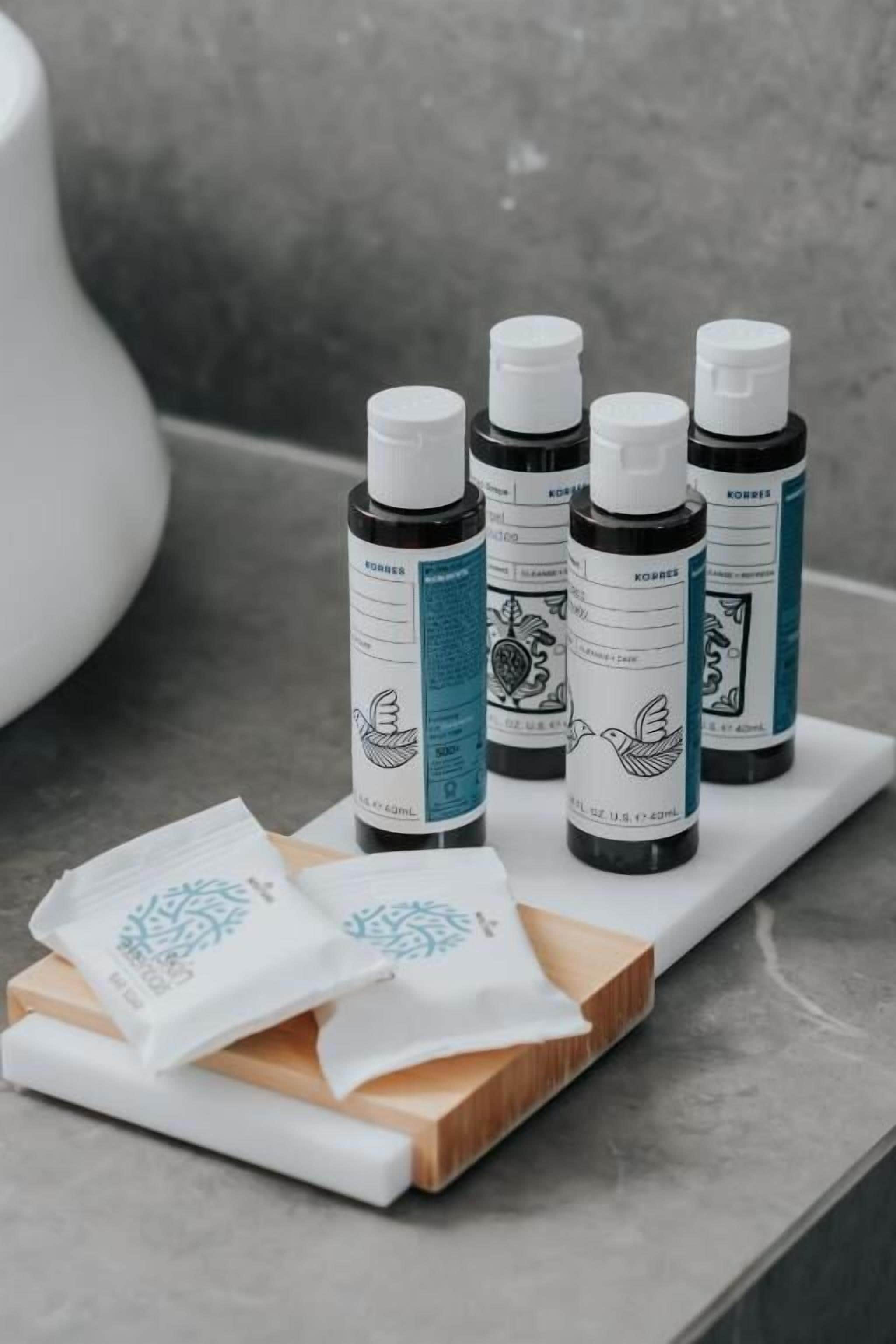 Four bottles of essential oils on a wooden tray with white cloth packets.