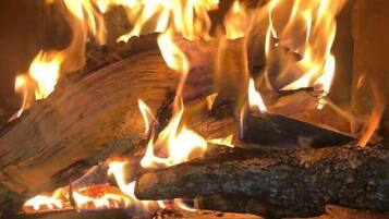 A fireplace with burning logs and flames.