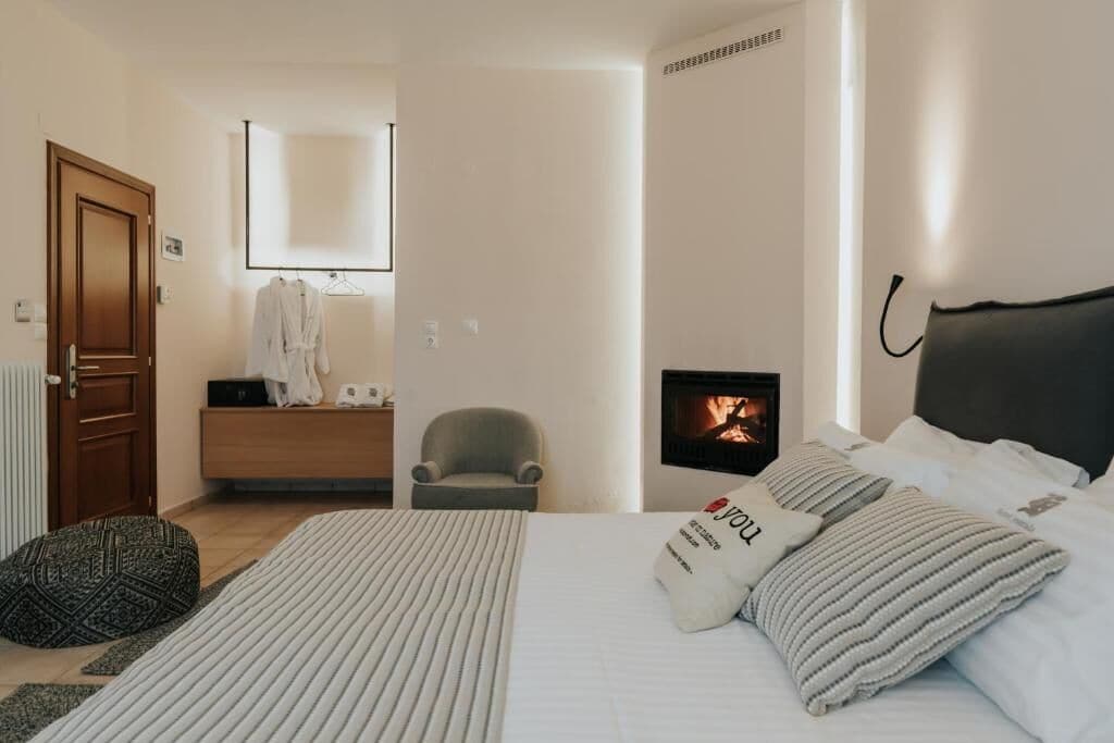 A bedroom with a bed, a chair, a bedside table, a mirror, and a fireplace.