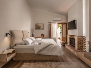 A bedroom with a bed, bedside table, lamp, and a fireplace.