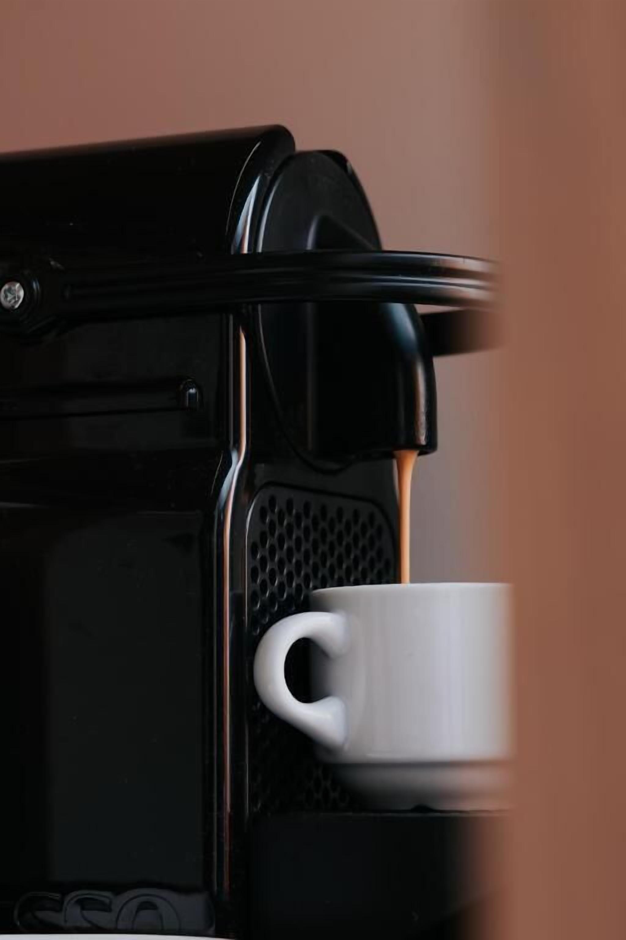 A coffee machine with a cup placed on its drip tray.