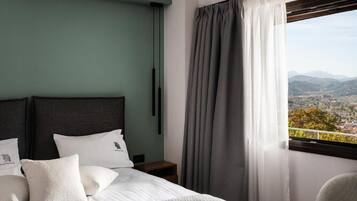 Una camera d'albergo con un letto, un comodino, una sedia e una finestra con tende.