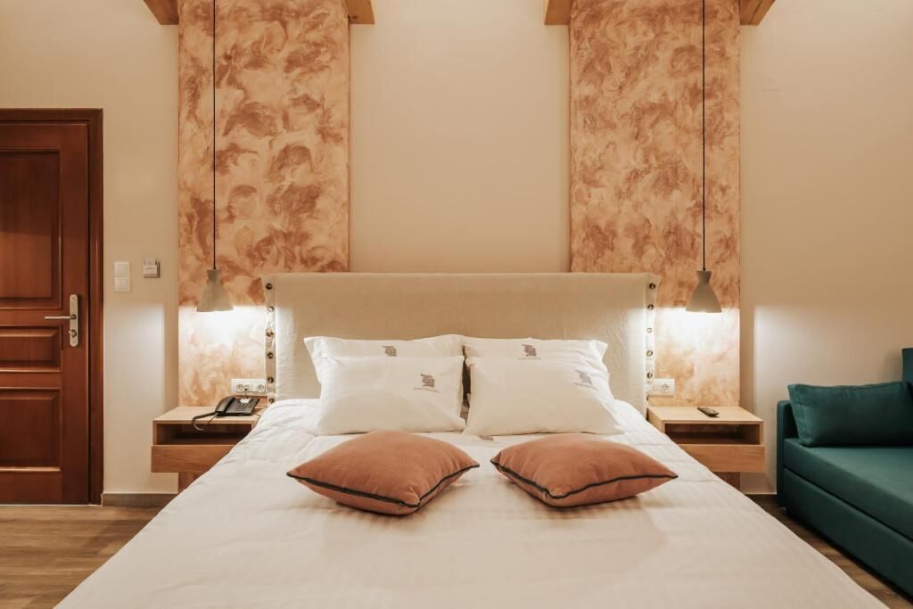 Een hotelkamer met een groot bed, twee nachtkastjes, een groene bank en een houten deur.