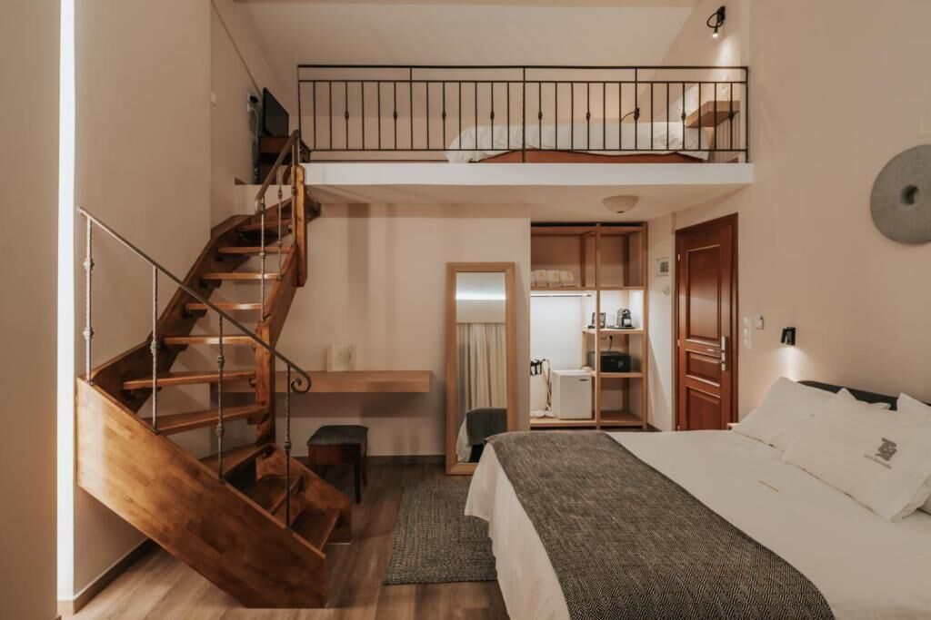 A bedroom with a wooden staircase, a bed with white bedding, a small desk, and a wardrobe.