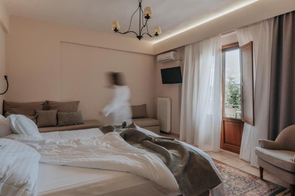 Een hotelkamer met een bed, een bank, een televisie en uitzicht op het landschap.