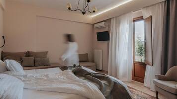 Een hotelkamer met een bed, een bank, een televisie en uitzicht op het landschap.