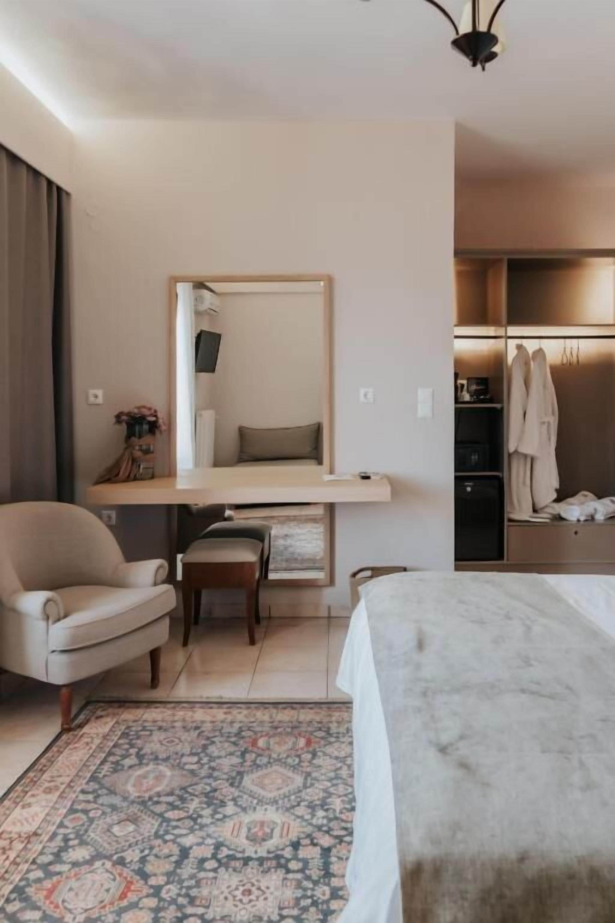 Ett hotellrum med en säng, ett skrivbord, en stol, en matta och en spegel.