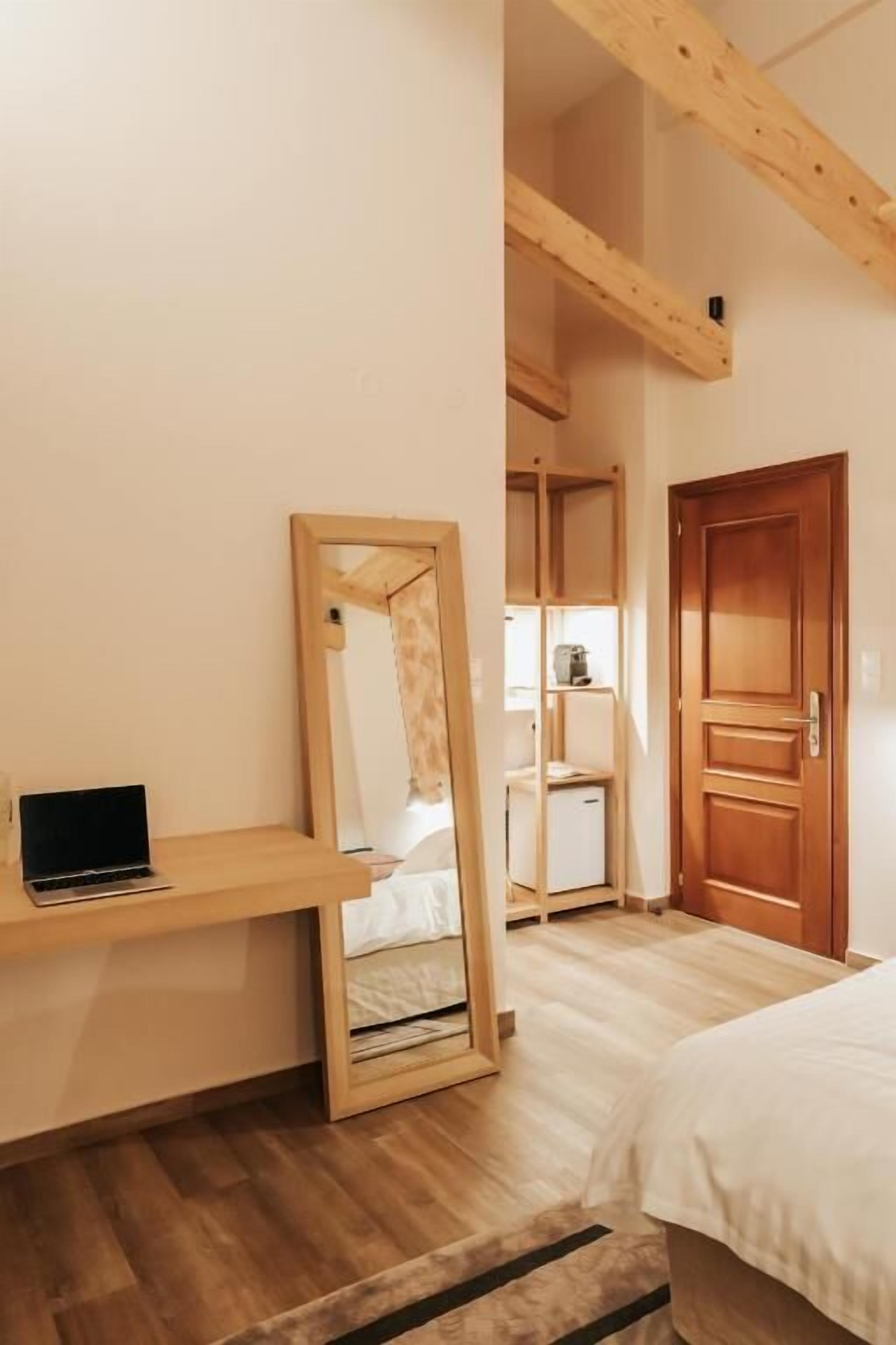 Un dormitorio con una cama, un escritorio de madera, un espejo y una puerta.