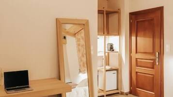 Un dormitorio con una cama, un escritorio de madera, un espejo y una puerta.