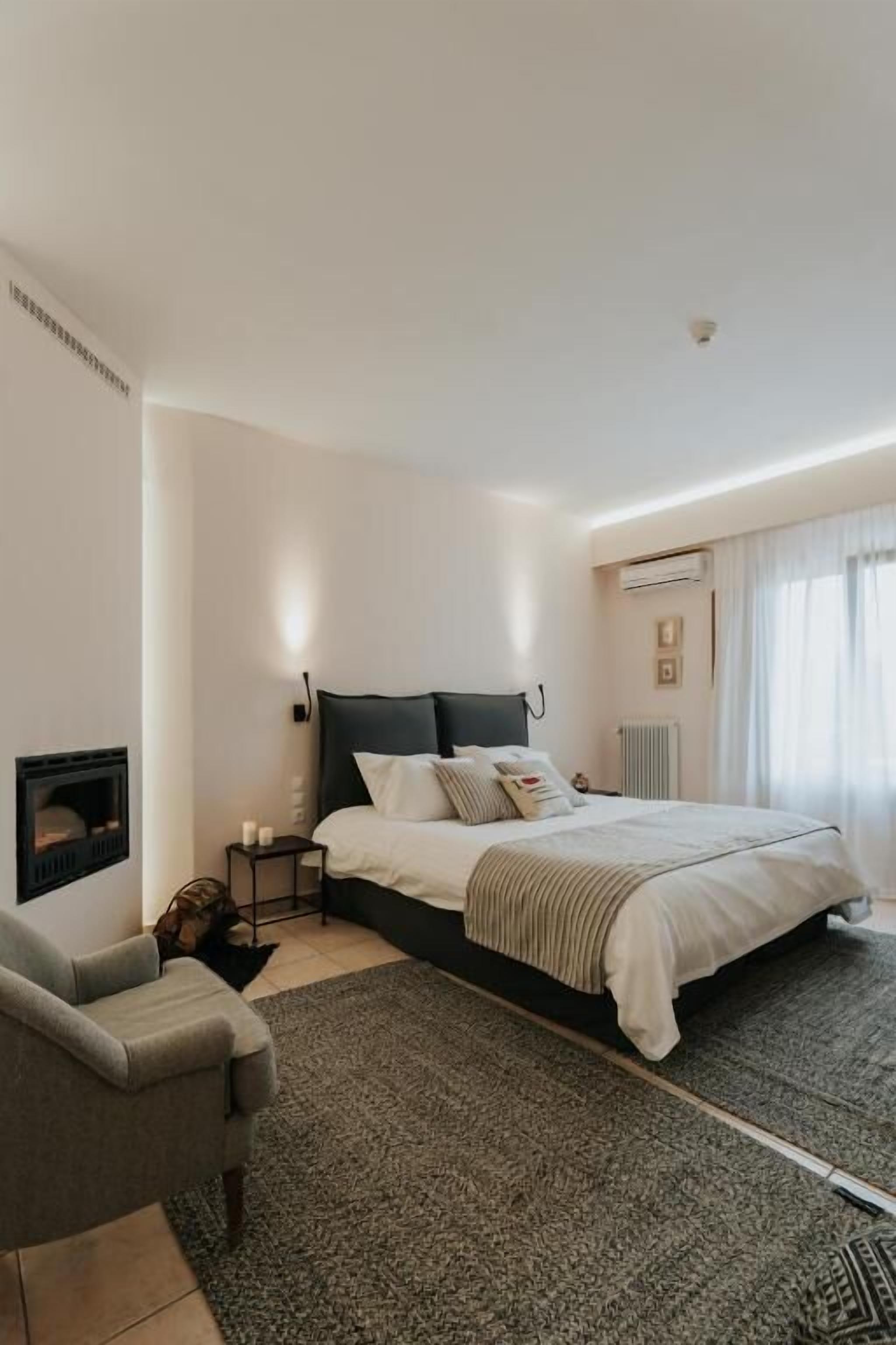 Un dormitorio moderno con una cama grande, una mesita de noche, una silla y una chimenea.