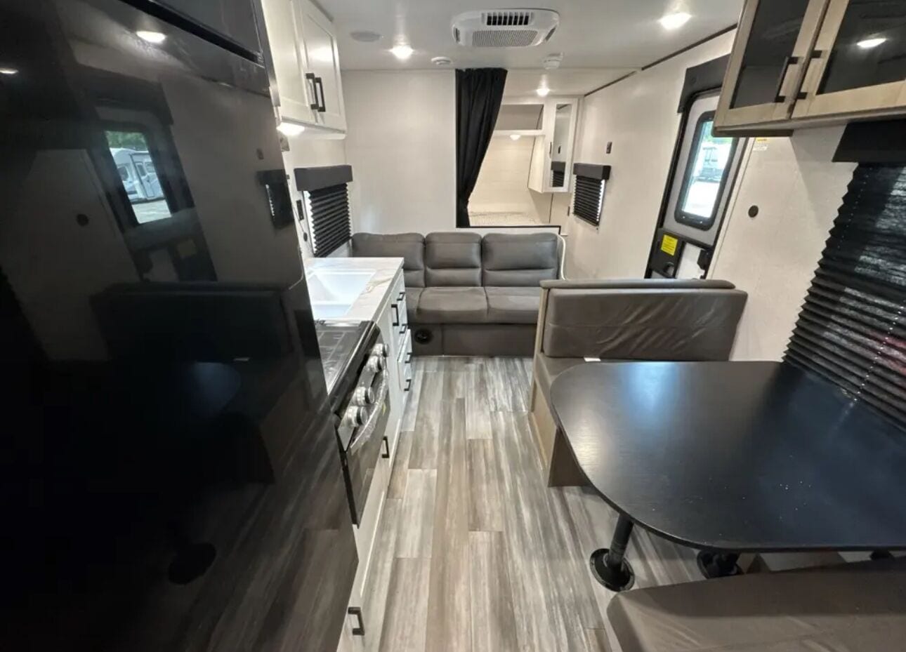Un intérieur de camping-car compact comprenant un coin cuisine, un espace salon et une petite table.