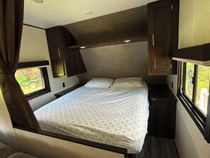 A bedroom with a bed, a window, and a small table. - RV with great Mountain View with picnic area, ponds, trails and fruits trees (Hamden)