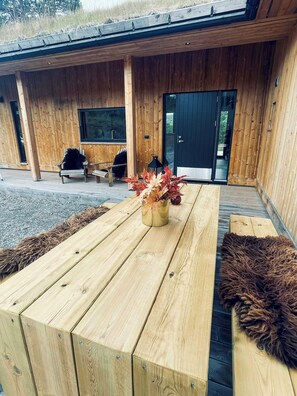 A wooden deck with a table, chairs, and a decorative plant.