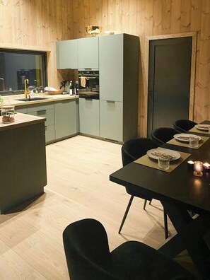 A modern kitchen with grey cabinets, a dining table set for two, and a wooden floor.
