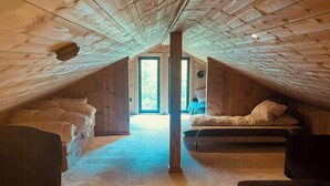 An attic bedroom with a sloped ceiling, two beds, a large window, and a view of the outdoors. - High ceilings with a view of the ski slopes (Hovden)