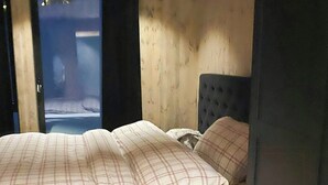 A room with a bed, a wooden floor, and a view through an open door. - High ceilings with a view of the ski slopes (Hovden)