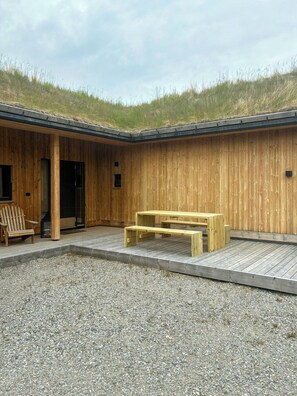 Ein Holzbau mit Gründach, Kiesterrasse und einer Holzbank.