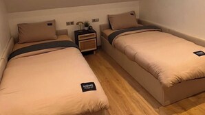 Een kleine, eenvoudige kamer met twee bedden, een raam met uitzicht en een schuine kap.