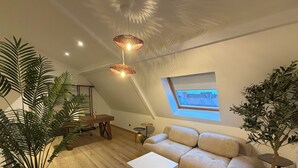 Een gezellig loft met schuine wand, een inbouwkantoor, een bank en een kleintje eettafel.