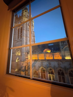 Een raam met uitzicht op een historisch gebouw met boogvensters en een klokkentoren.
