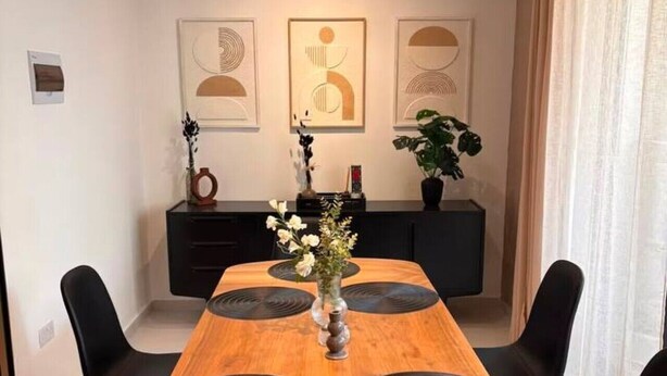 A dining area with a wooden table, black chairs, and a vase with flowers. - Beautiful 3BR home Apartment in Gzira w/WIFI & AC (Il-Gżira)