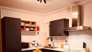A modern kitchen with a marble island, black cabinetry, and stainless steel appliances. - Beautiful 3BR home Apartment in Gzira w/WIFI & AC (Il-Gżira)