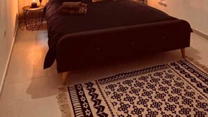 A bedroom with a bed, bedside lamps, a wall-mounted shelf with decorative items, and a unique ceiling light fixture. - Beautiful 3BR home Apartment in Gzira w/WIFI & AC (Il-Gżira)