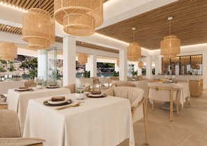 A modern dining area with multiple tables, wicker pendant lights, and a view of a rocky landscape through large windows. - Villa Sirena – Seafront Boutique Hotel AO (Cala Figuera)