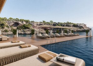 A poolside area with lounge chairs and a wooden deck. - Villa Sirena – Seafront Boutique Hotel AO (Cala Figuera)