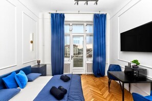 Ein modernes Hotelzimmer mit Bett, Schreibtisch, Stuhl und einem großen Fenster mit Vorhängen.