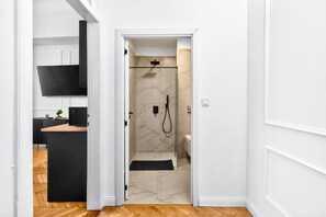A modern bathroom with a shower, toilet, and a small sink area. - Breathtaking River & Hill Views in the Heart of Budapest – 619 (Budapest)
