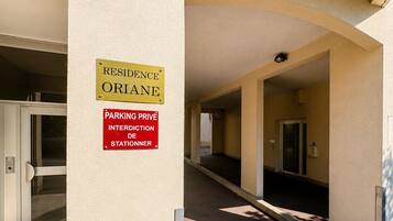 A building entrance with a sign indicating private parking and a residence named 'ORIANE.'