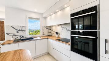 Eine moderne Küche mit weißen Schränken, einer Marmor-Spritzschutzwand und einem eingebauten Backofen.