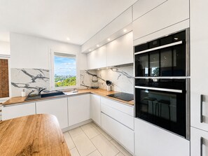 Una cucina moderna con mobili bianchi, una schiena di marmo e un forno integrato.