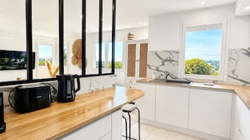 Una cocina moderna con encimera de madera, una cafetera negra y vistas al exterior con vegetación.