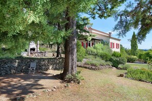 A stone wall, a wooden bench, and a building with red shutters.