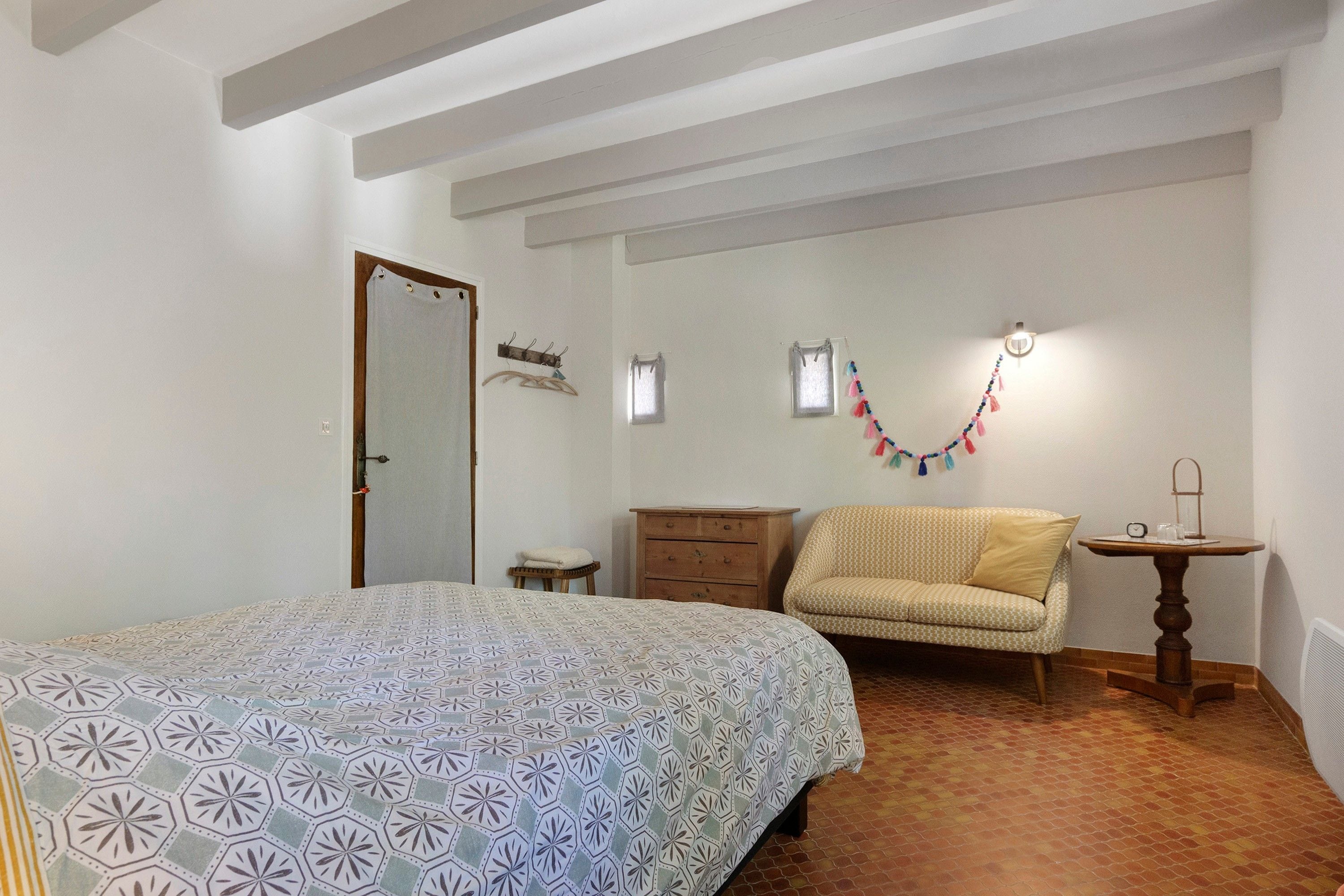 Ein Schlafzimmer mit einem Bett, einem Sessel, einem Schminktisch und einem kleinen Tisch mit einer Lampe.