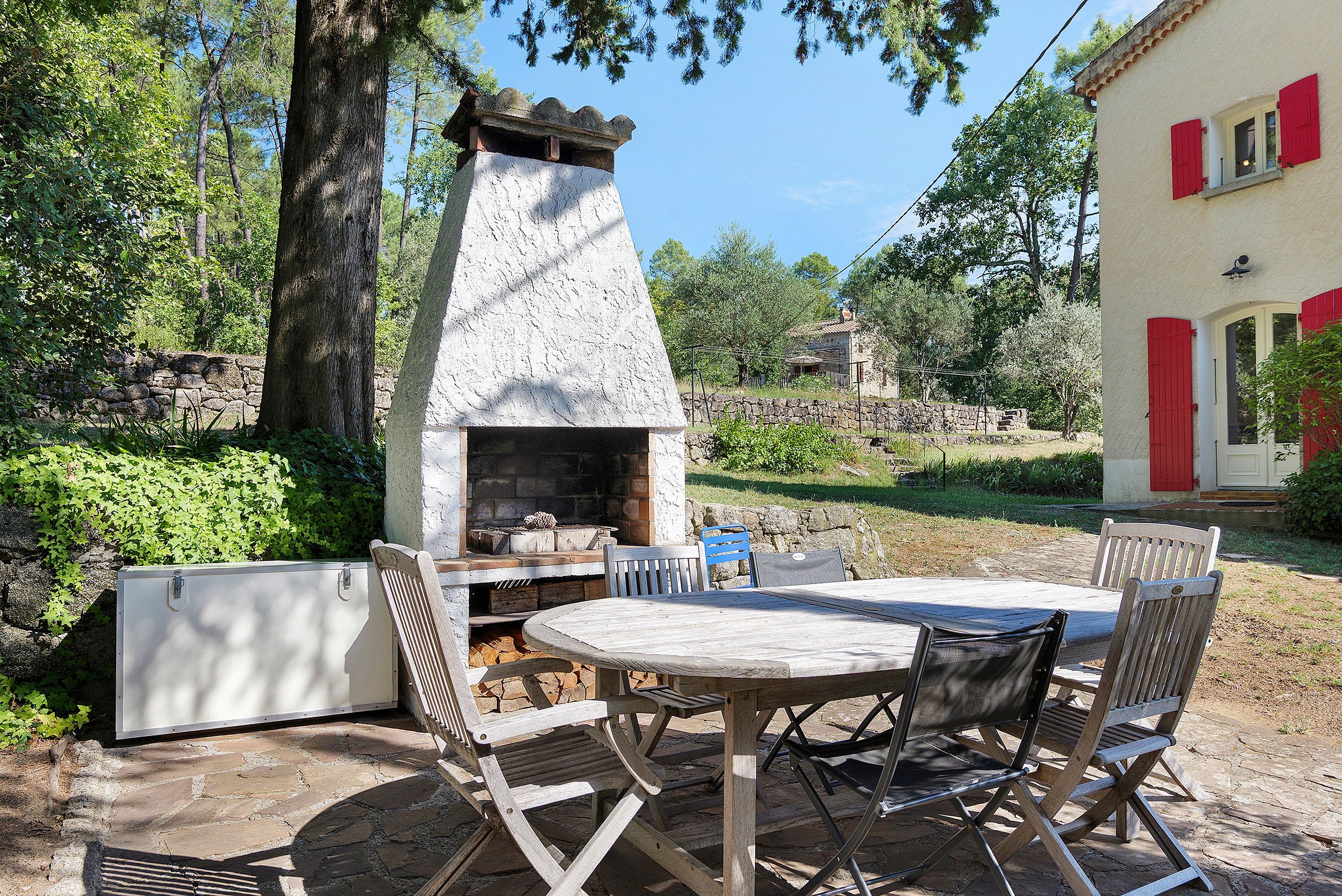 An outdoor patio with a stone-built wood-fired oven, a table, and chairs.