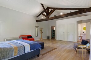 A bedroom with a large bed, a bedside table, a chair, a wardrobe, and a bathroom visible through an open door. - Villa Oléandre with Large Private Pool, Chassiers Ardèche (Chassiers)