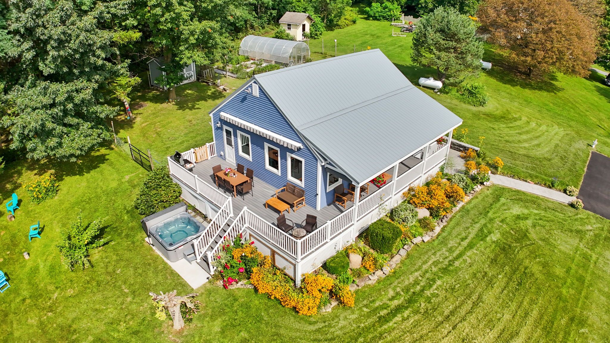 A two-story house with a covered patio, a hot tub, and a well-maintained lawn.