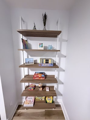 Una estantería de madera con varios niveles que contiene libros, un cuadro enmarco y objetos decorativos.