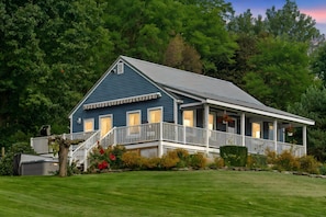 A two-story house with a porch, surrounded by a well-maintained lawn and trees.