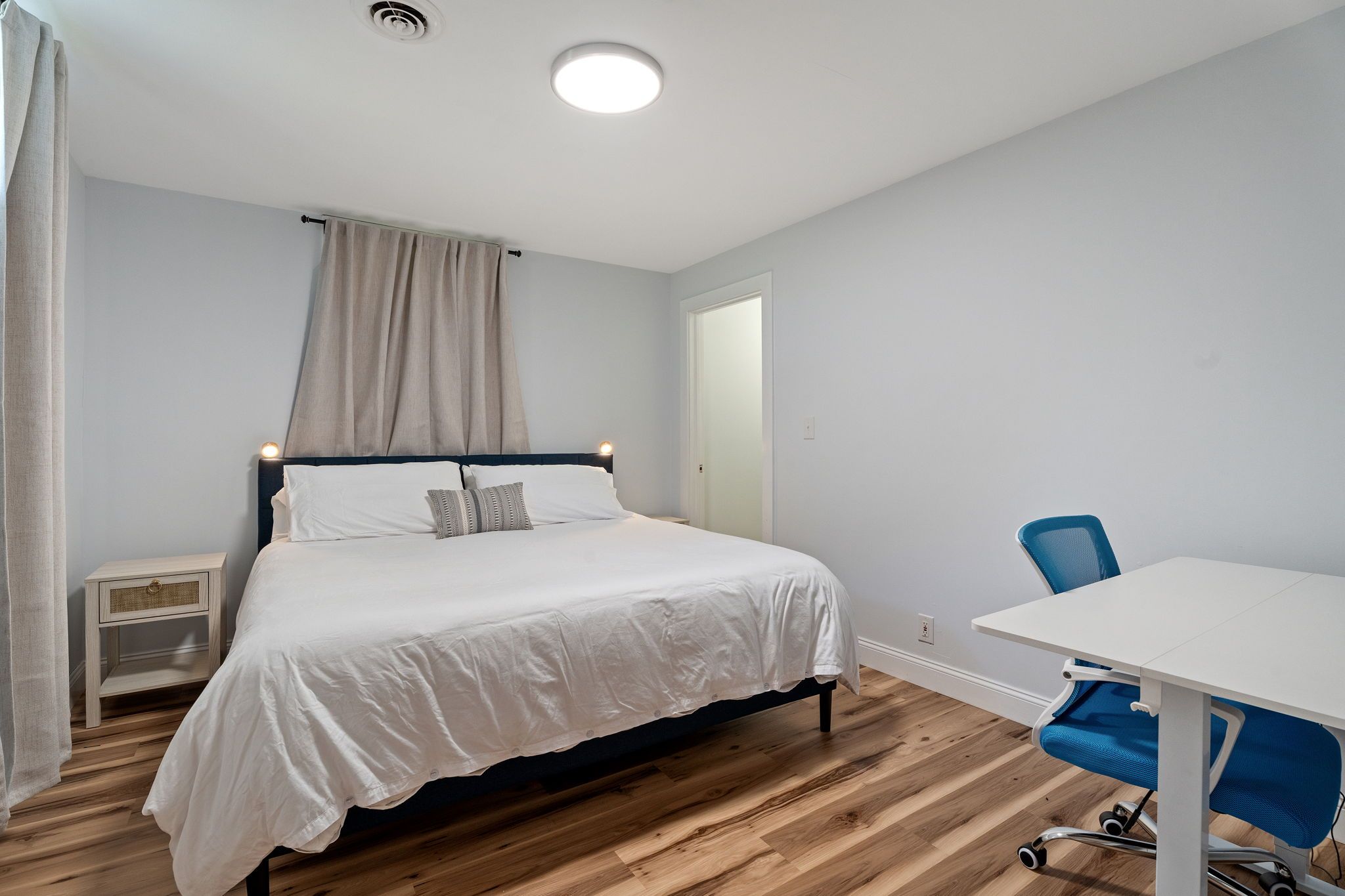 Une chambre à coucher comprenant un lit, une table de chevet, une chaise et un bureau avec une autre chaise.