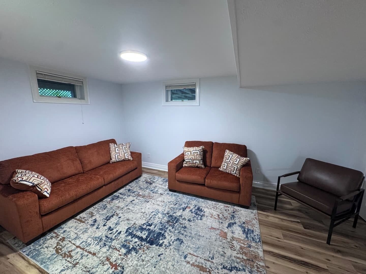 A living room with two brown sofas, a patterned rug, and a wooden floor.