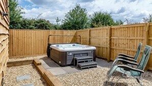 A hot tub with steps and a seating area, surrounded by a wooden fence and gravel. - The Hay Barn at Rusty Lane Farm (Seend)