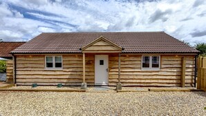 A wooden cabin with a tiled roof, a front door, and two windows. - The Hay Barn at Rusty Lane Farm (Seend)