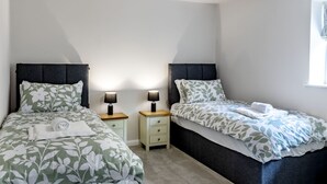 A twin room with two single beds, bedside tables, lamps, and a window. - The Hay Barn at Rusty Lane Farm (Seend)