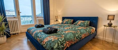 Quarto com cama, vista da cidade e um vaso de planta.