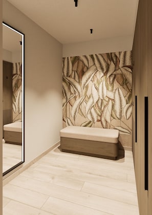 Un baño moderno con un espejo grande, un banco y una pared con diseño de hojas.