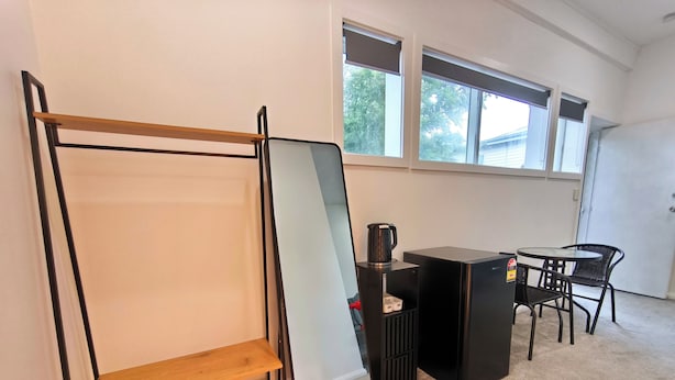 Una habitación con cama, escritorio, silla, cafetera y ventana.